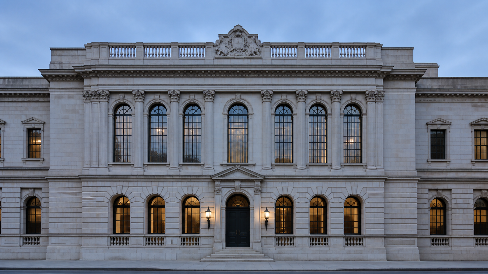 The limestone front of a large private bank at dusk, its arched windows lit from inside.